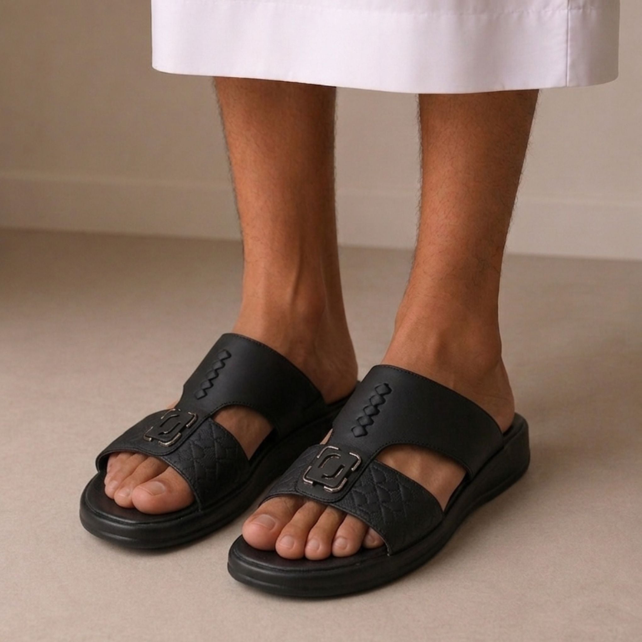 Black sandals worn with a white skirt on a neutral background